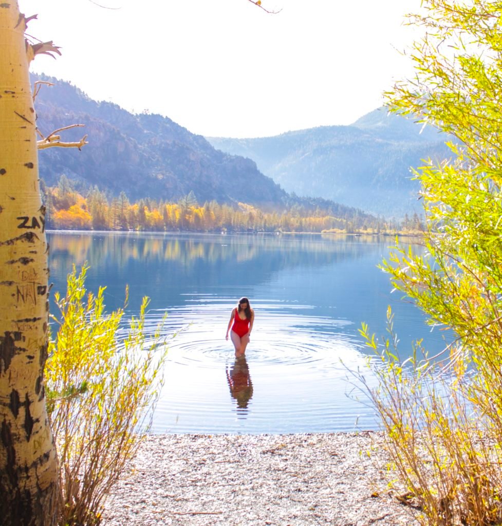 woman in a red swimsuit in a lake in the mountains in fall